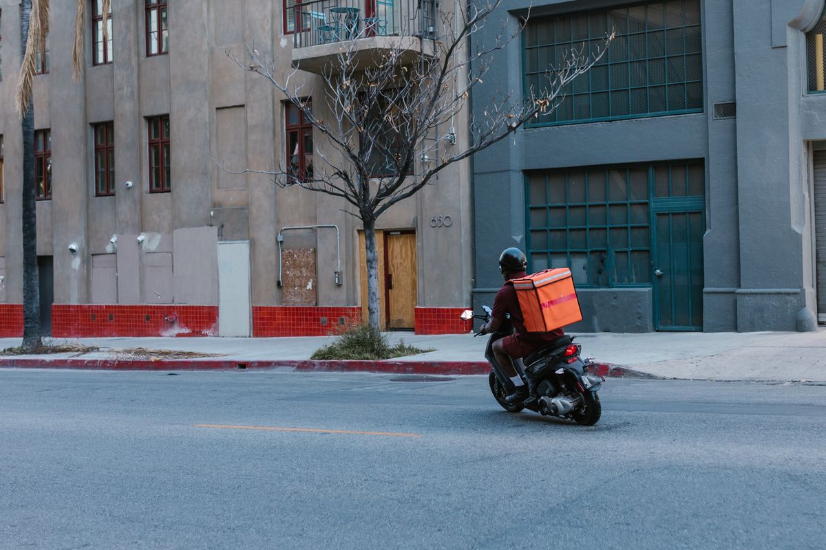 Motorizado ALTOKE en ruta de reparto con la caja de entrega
